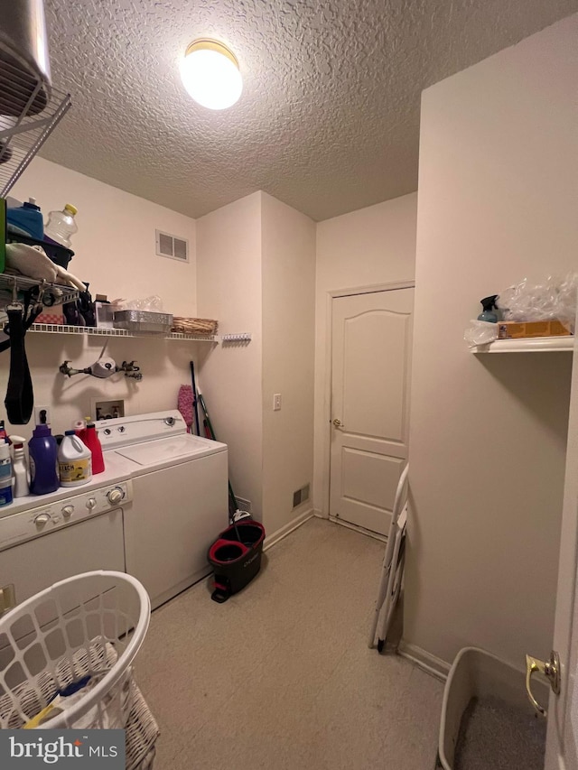 clothes washing area featuring a textured ceiling and washing machine and clothes dryer