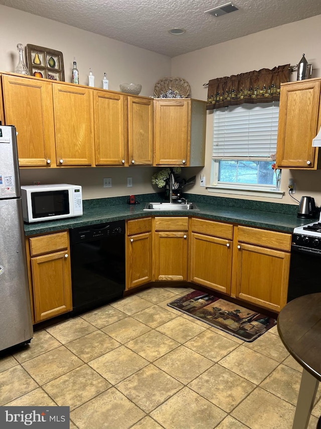 kitchen featuring gas stove, sink, a textured ceiling, stainless steel fridge, and black dishwasher