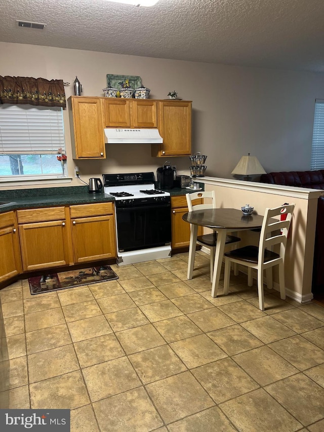 kitchen featuring light tile patterned floors, gas range, and a textured ceiling