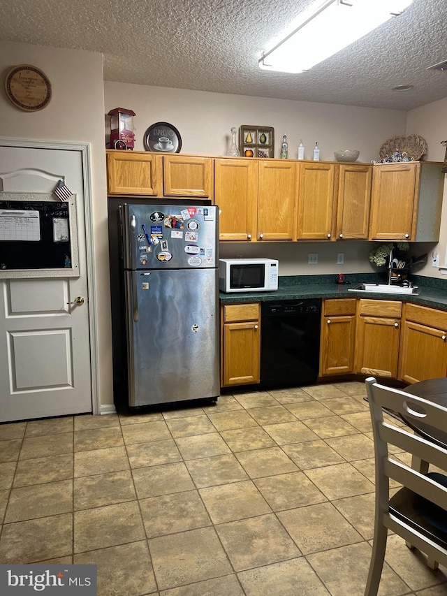 kitchen featuring stainless steel refrigerator, dishwasher, sink, and a textured ceiling