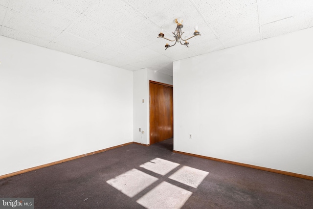 carpeted empty room featuring an inviting chandelier