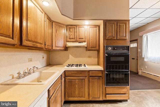 kitchen with sink, a paneled ceiling, baseboard heating, white gas stovetop, and double oven