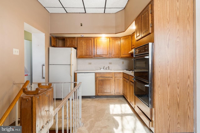 kitchen with a drop ceiling, sink, and white appliances