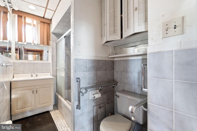 full bathroom featuring toilet, tile walls, vanity, enclosed tub / shower combo, and tile patterned flooring