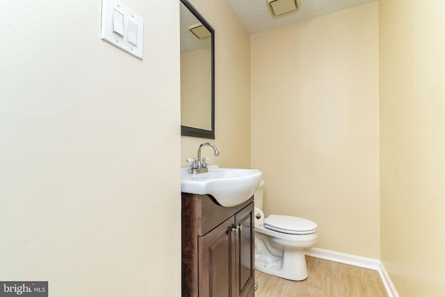 bathroom featuring vanity, hardwood / wood-style floors, a textured ceiling, and toilet