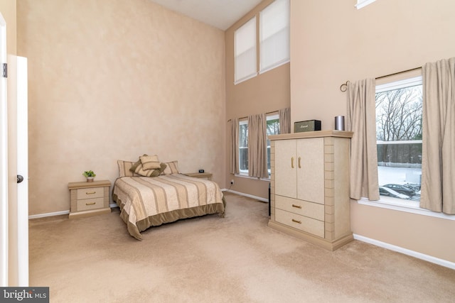 carpeted bedroom with a towering ceiling and multiple windows