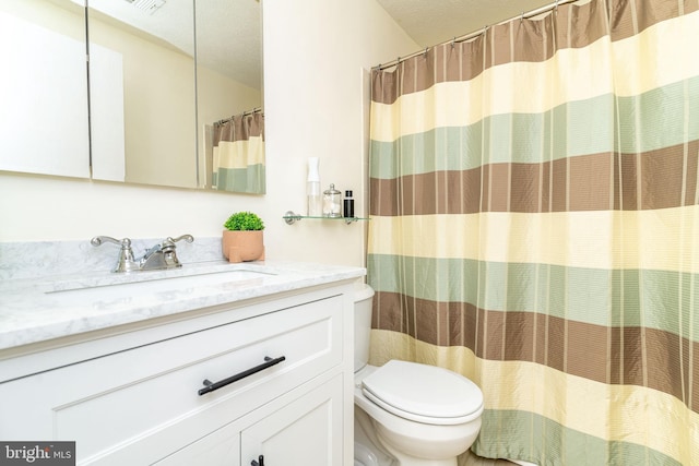 bathroom with vanity, walk in shower, a textured ceiling, and toilet