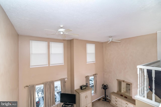 unfurnished living room featuring ceiling fan, light colored carpet, and a textured ceiling