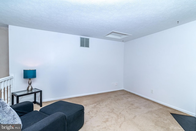 sitting room featuring light colored carpet and a textured ceiling