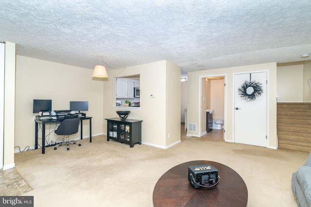 carpeted home office featuring a textured ceiling