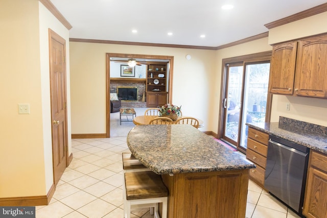 kitchen with ornamental molding, stainless steel dishwasher, dark stone counters, and a kitchen island