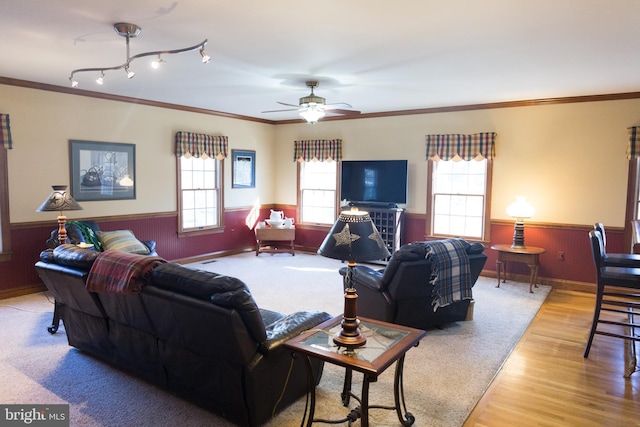 living room with ornamental molding, wooden walls, ceiling fan, and light hardwood / wood-style floors