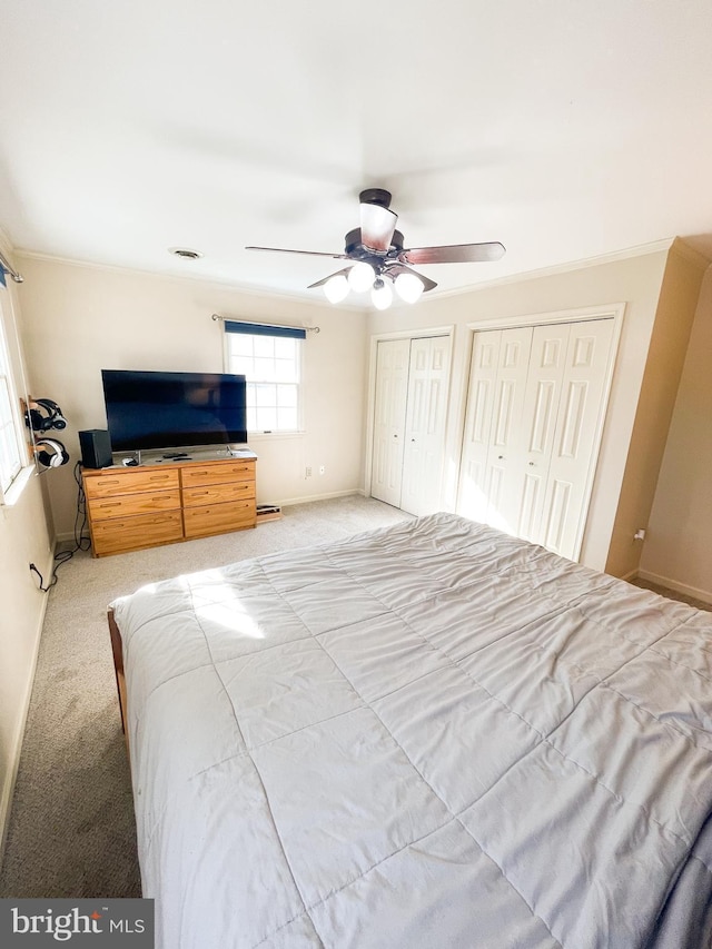 carpeted bedroom with two closets and ceiling fan