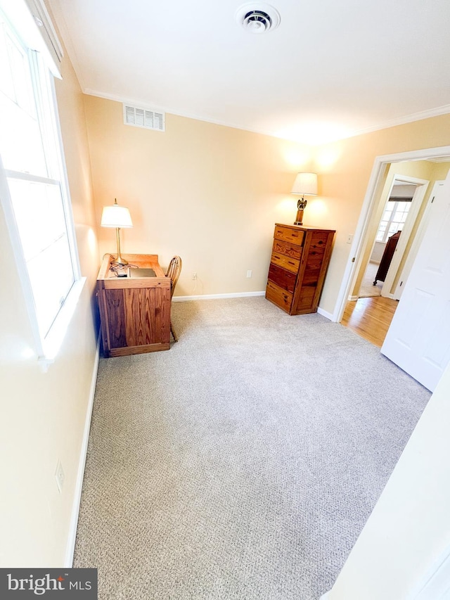 sitting room with ornamental molding and light carpet