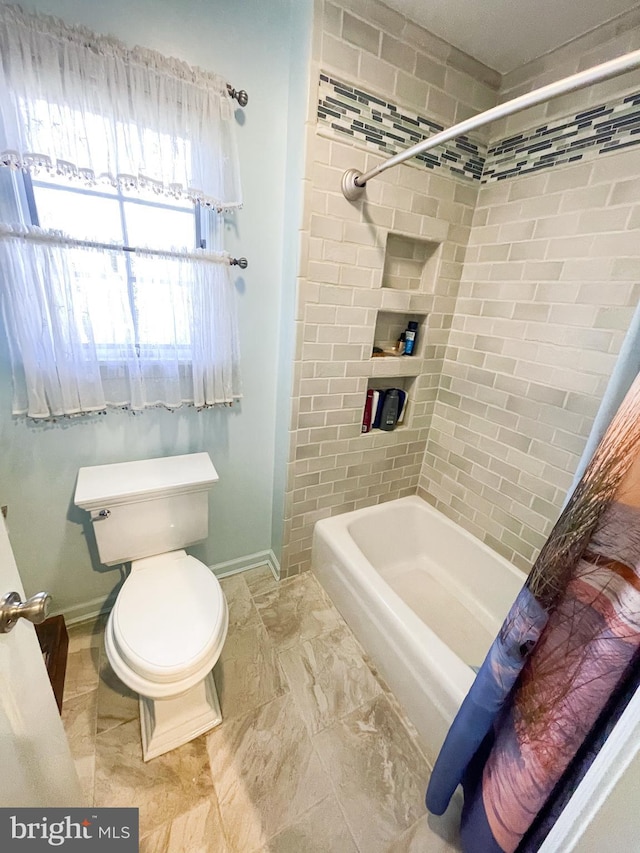 bathroom featuring shower / bathtub combination with curtain and toilet