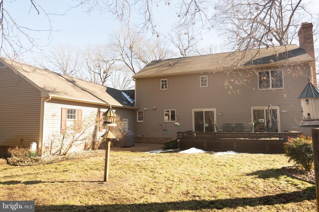 rear view of property featuring a wooden deck and a lawn