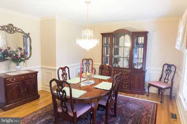 dining space with an inviting chandelier, crown molding, and light hardwood / wood-style flooring