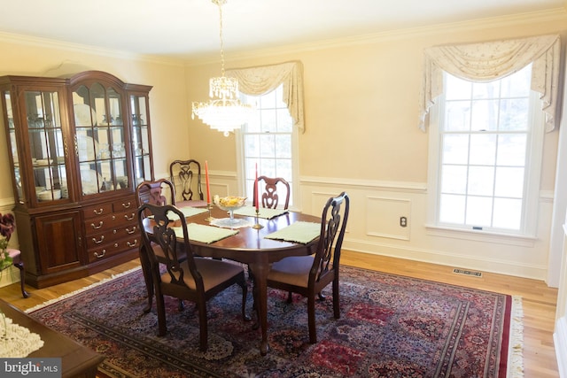 dining area with crown molding, an inviting chandelier, and light hardwood / wood-style floors