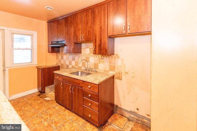 kitchen with light stone countertops, sink, and decorative backsplash