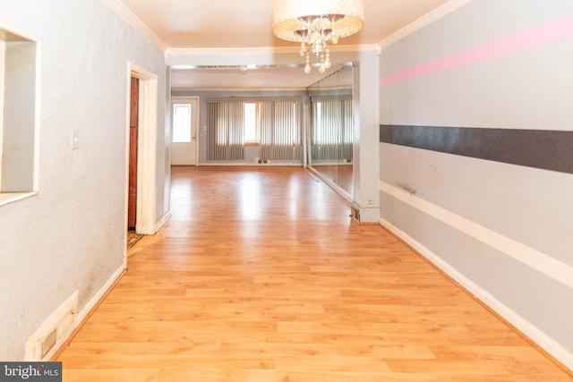 hall with light hardwood / wood-style flooring, ornamental molding, and a chandelier