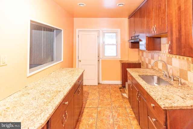 kitchen featuring light stone counters, sink, and decorative backsplash