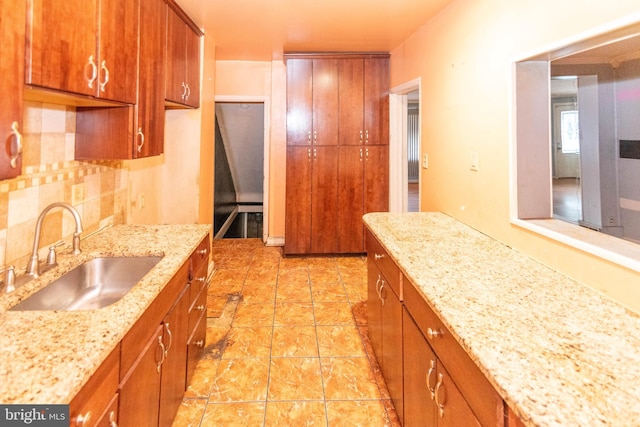 kitchen featuring tasteful backsplash, sink, and light stone countertops