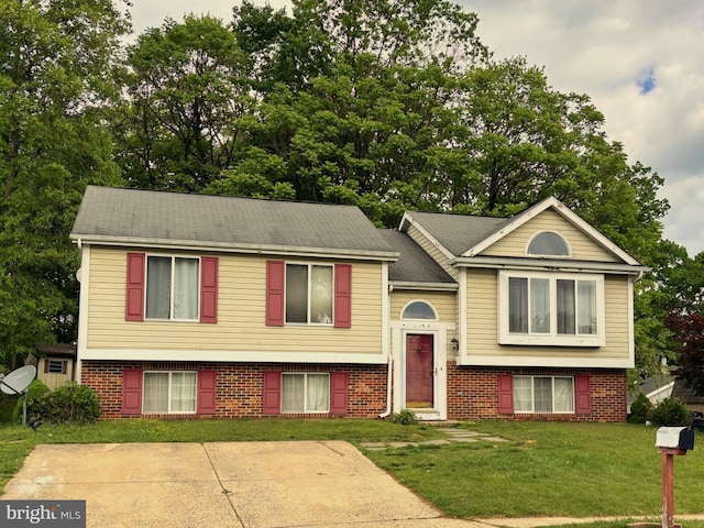 raised ranch with a front lawn and brick siding