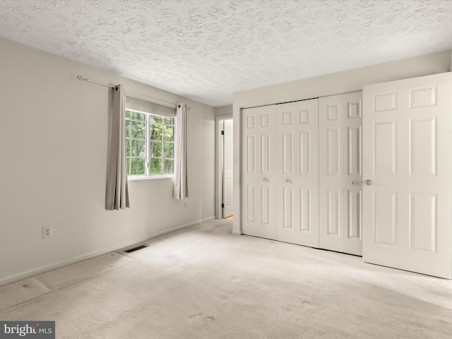 unfurnished bedroom featuring carpet floors, a closet, a textured ceiling, and baseboards