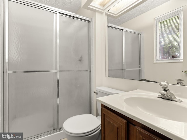 bathroom with toilet, a stall shower, a textured ceiling, and vanity