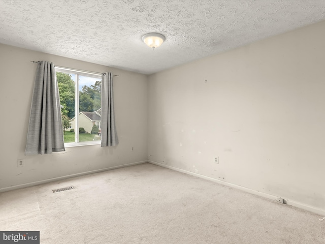 spare room featuring carpet flooring, baseboards, and a textured ceiling