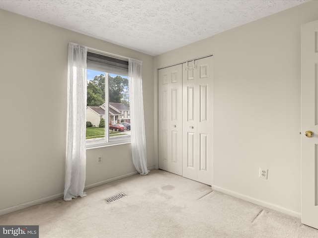 unfurnished bedroom with carpet, baseboards, a closet, and a textured ceiling