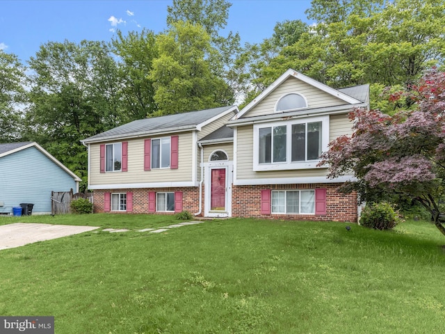 raised ranch with a front lawn and brick siding