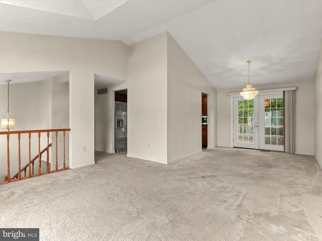 unfurnished living room featuring a chandelier, lofted ceiling, carpet floors, and baseboards