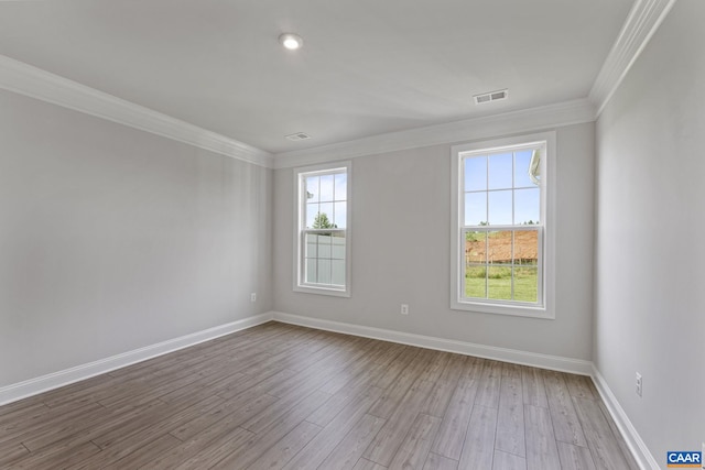 unfurnished room with ornamental molding and light wood-type flooring