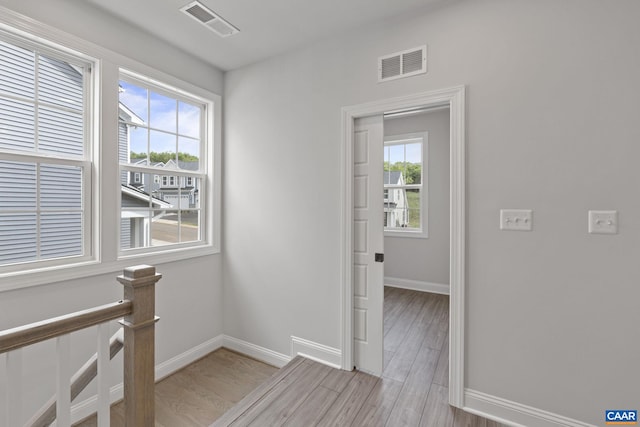 corridor with a healthy amount of sunlight and light hardwood / wood-style floors