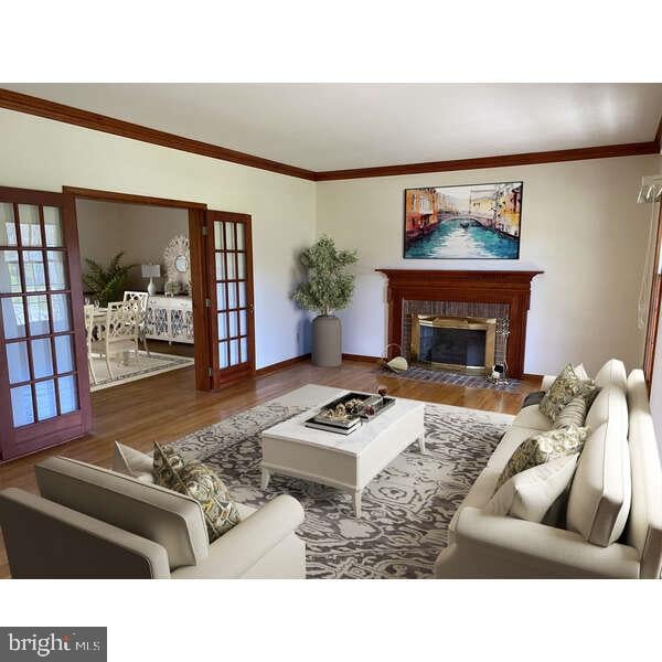 living room featuring hardwood / wood-style flooring, a fireplace, and crown molding