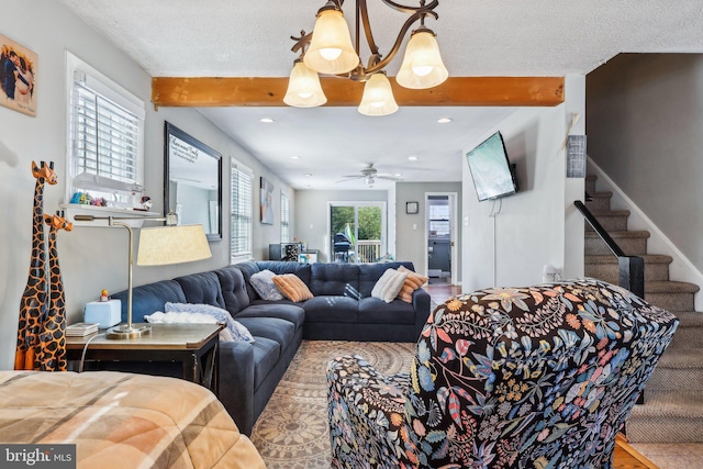 living room with ceiling fan, a textured ceiling, and beamed ceiling