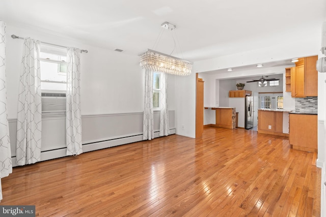 unfurnished living room with ceiling fan, a healthy amount of sunlight, and light wood-type flooring