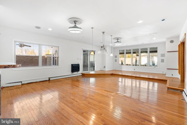 unfurnished living room featuring a baseboard radiator, heating unit, and light hardwood / wood-style floors