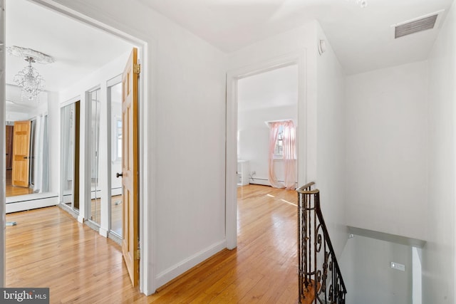 hall featuring a notable chandelier, a baseboard radiator, and light wood-type flooring