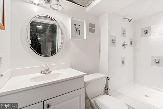 bathroom featuring vanity, tiled shower, and toilet