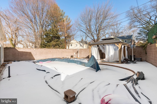 yard layered in snow with a gazebo and a covered pool