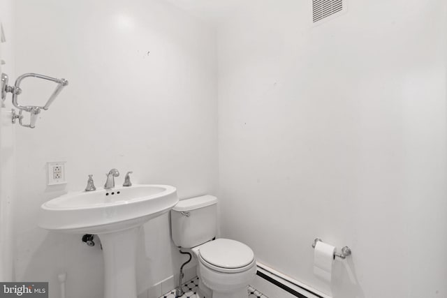 bathroom with toilet, sink, and a baseboard heating unit