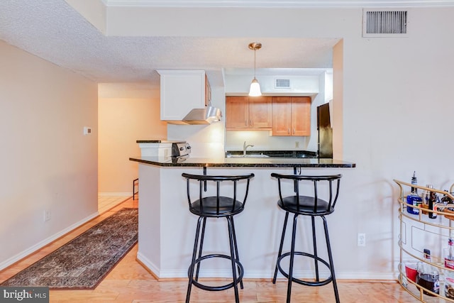 kitchen with sink, kitchen peninsula, a kitchen breakfast bar, and dark stone counters