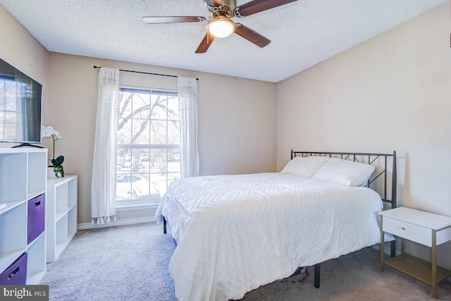 carpeted bedroom featuring multiple windows, a textured ceiling, and ceiling fan