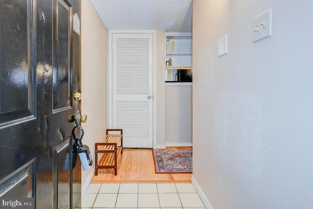 interior space featuring light tile patterned floors, a textured ceiling, and built in shelves