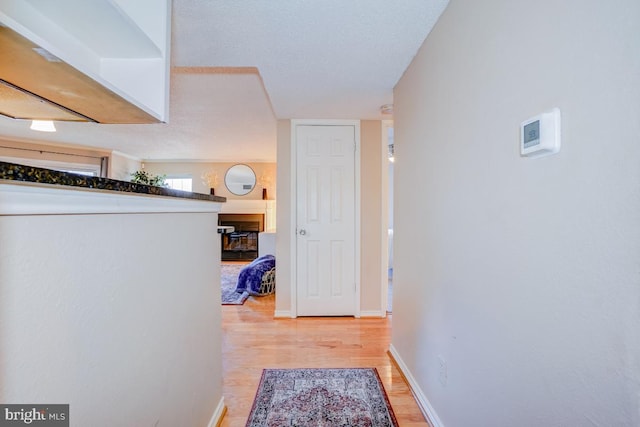 hallway with light hardwood / wood-style flooring and a textured ceiling