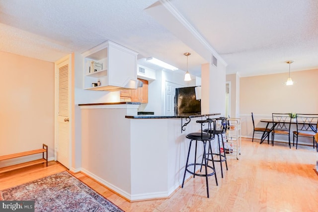 kitchen featuring pendant lighting, white cabinetry, kitchen peninsula, and black fridge