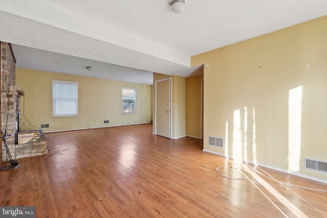 unfurnished living room with a textured ceiling and light wood-type flooring