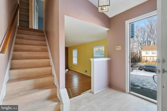 stairway with lofted ceiling and hardwood / wood-style floors